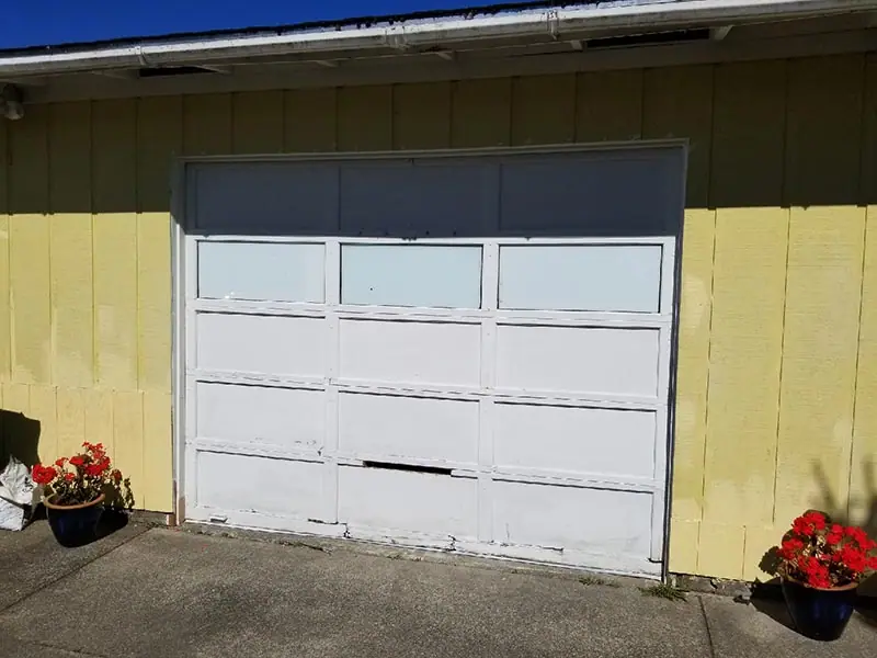 Before: dented white garage door