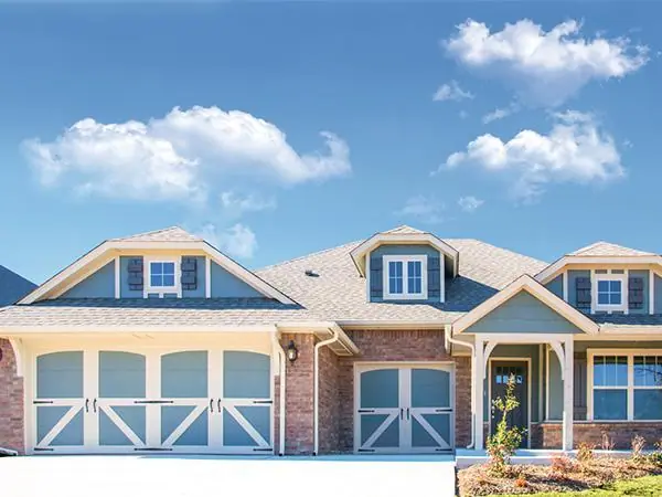 Carriage-style garage doors on a blue and brick home